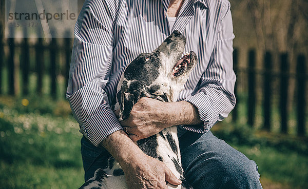 Älterer Mann umarmt seinen dalmatinischen Hund