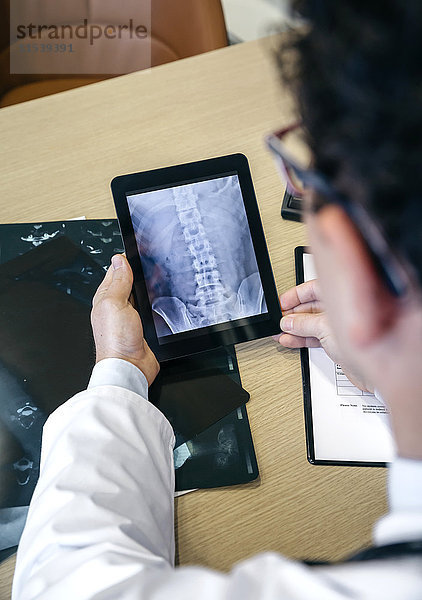 Arzt betrachtet Röntgenbild auf digitalem Tablett