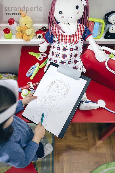 Draufsicht des kleinen Mädchens beim Zeichnen ihrer Puppe