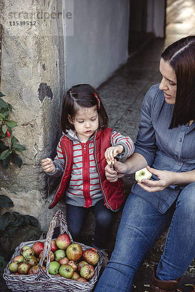 Mutter und ihre kleine Tochter mit frisch geernteten Bio-Äpfeln