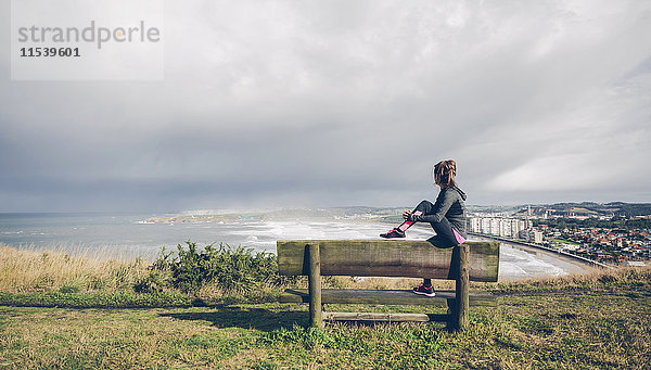 Sportliche mittlere erwachsene Frau auf Klippe mit Blick aufs Meer