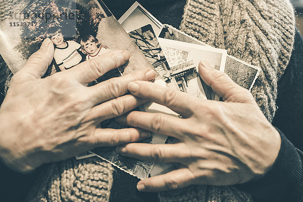 Hände der älteren Frau mit alten Fotos  Nahaufnahme