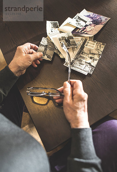 Hände einer älteren Frau mit alter Fotografie und Brille