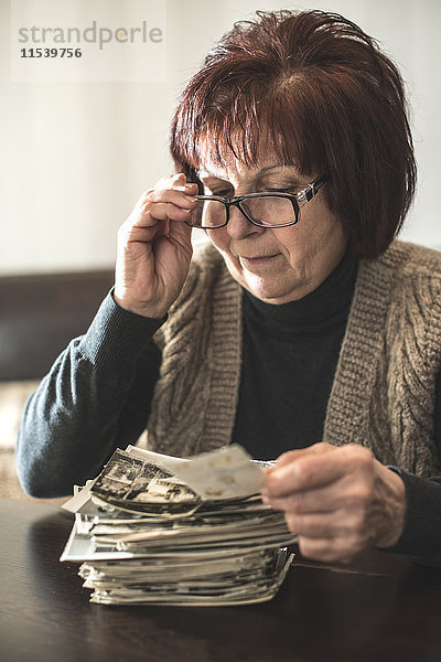 Seniorin mit Stapel alter Fotografien