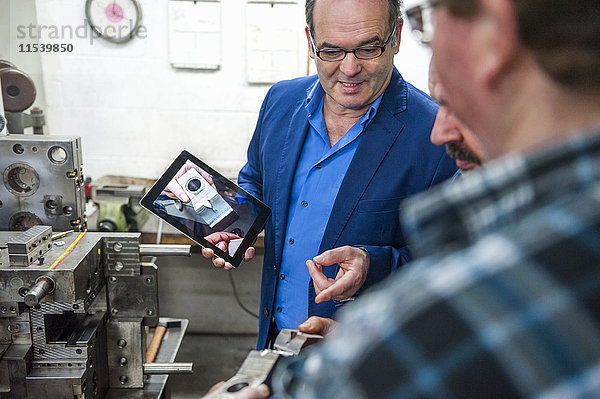 Drei Männer mit digitalem Tablett diskutieren über ein Werkstück