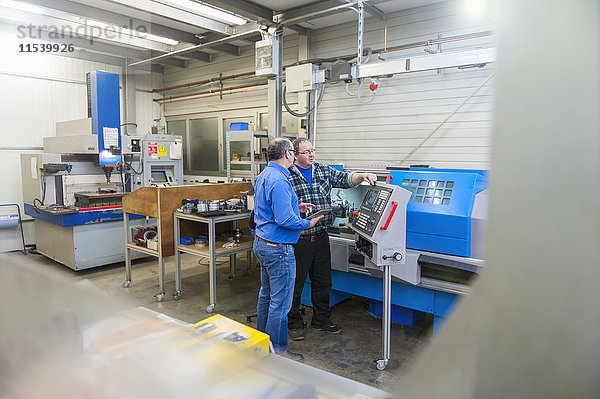 Zwei Männer in der Fabrik reden an der Maschine für den Formenbau