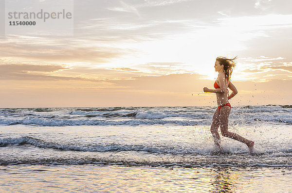Frau im Bikini beim Joggen am Meer
