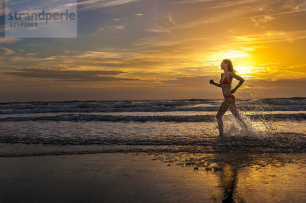Frau im Bikini beim Joggen am Meer