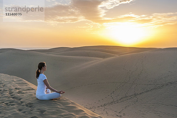 Frau praktiziert Yoga auf Sanddünen