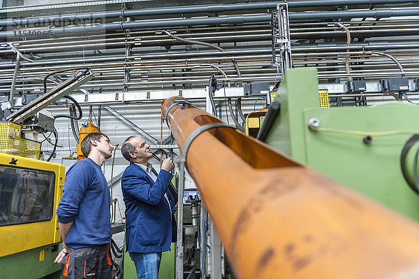 Zwei Leute in der Kunststofffabrik untersuchen Maschinen