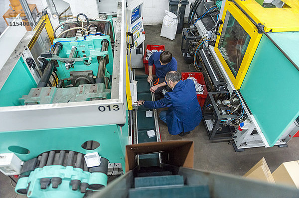 Zwei Leute in der Kunststofffabrik untersuchen Maschinen
