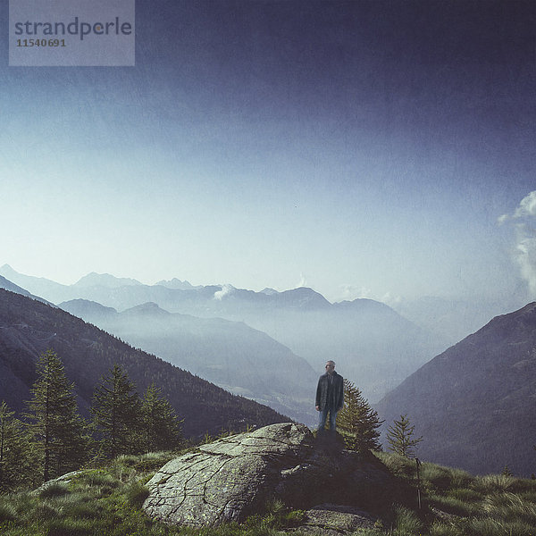 Italien  Lombardei  Chiesa in Valmalenco  Mann im Morgenlicht auf einem Felsen stehend