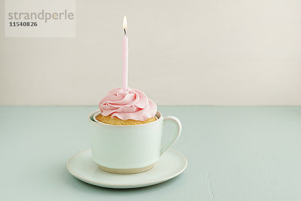 Tasse Kuchen mit angezündeter Kerze in einer Tasse