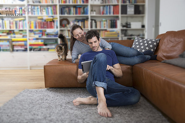 Erwachsenes Paar auf dem Sofa liegend  mit digitalem Tablett