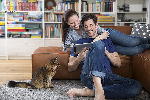 Erwachsenes Paar auf dem Sofa liegend  mit digitalem Tablett
