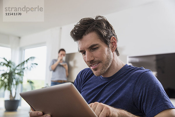 Mann zu Hause mit digitalem Tablett