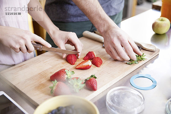 Paare schneiden Erdbeeren in der Küche