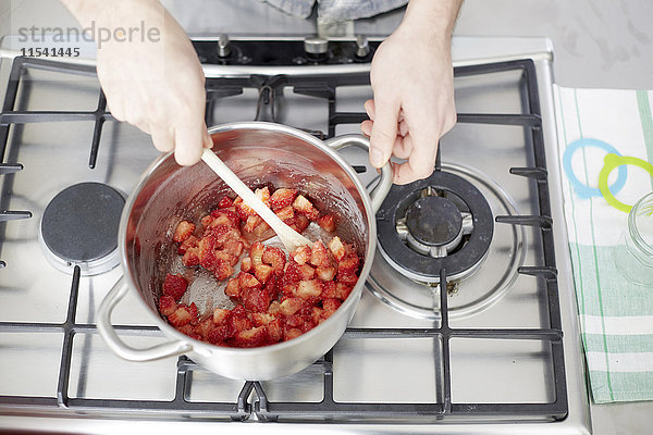 Mann rührt Erdbeeren auf Gasherd