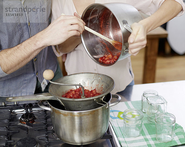 Paar Zubereitung von heißen Erdbeeren auf dem Gasherd