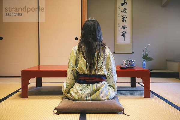 Japan  Uji  Rückansicht einer Frau  die Yukata trinkt und Tee in einem traditionellen japanischen Zimmer trinkt.