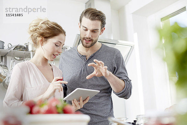 Paar betrachtet digitales Tablett in der Küche