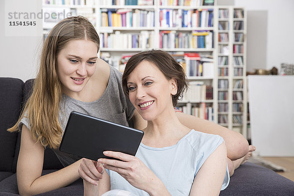 Mutter und erwachsene Tochter teilen sich ein digitales Tablett