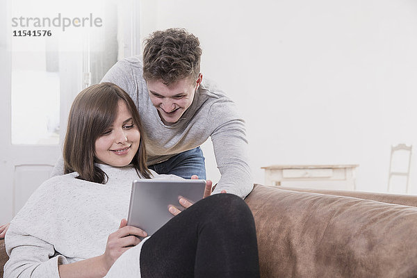 Glückliches junges Paar zu Hause mit digitalem Tablett