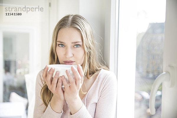 Porträt einer blonden Frau mit einer Schale Kaffee