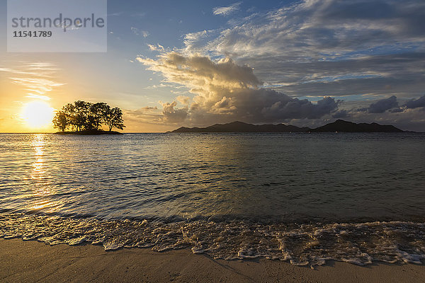 Seychellen  La Digue  Anse Source D'Argent  Praslin Island im Hintergrund  kleine Insel mit Bäumen bei Sonnenuntergang