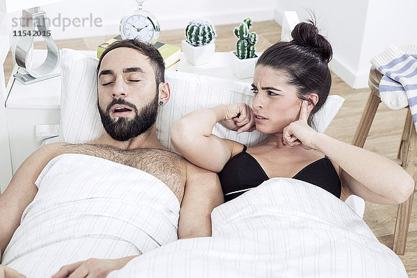 Paar im Bett liegend mit Mann schnarchend