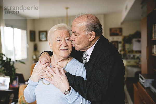 Seniorenpaar  das sich zu Hause umarmt und küsst.