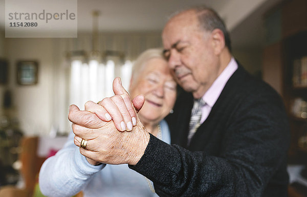 Hände des älteren Paares tanzen zusammen zu Hause