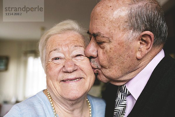 Ein älterer Mann küsst seine glückliche Frau.