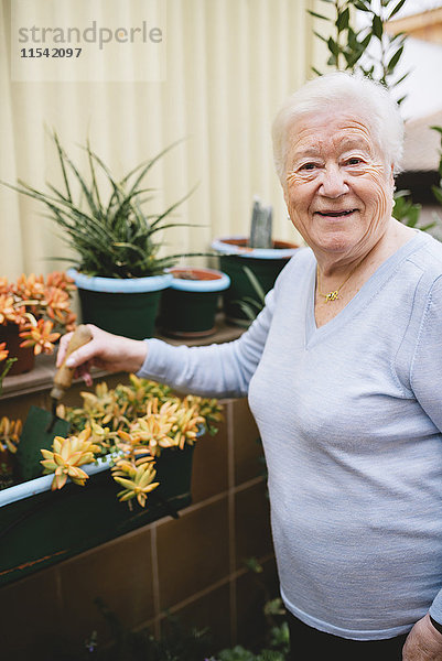 Porträt einer lächelnden Seniorin im Garten auf dem Balkon