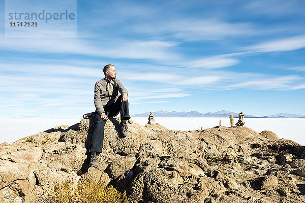 Bolivien  Atacama  Altiplano  Salar de Uyuni  Mann auf Stein sitzend
