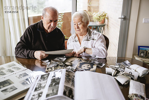 Seniorenpaar beim Betrachten ihrer alten Fotos und Fotoalben zu Hause