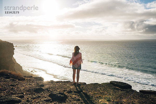 Spanien  Fuerteventura  El Cotillo  Rückansicht der Frau mit Blick auf das Meer bei Sonnenuntergang