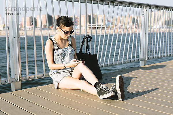USA  New York  Coney Island  junge Frau beim Telefonieren am Pier