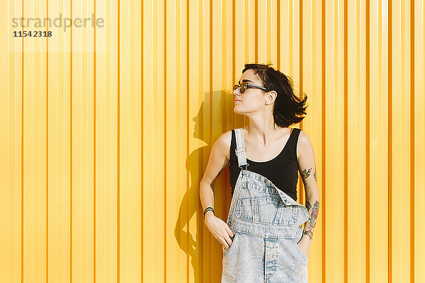 Junge Frau steht an einer gelben Wand