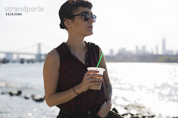 USA  New York City  Porträt einer jungen Frau mit Sonnenbrille und Plastikbecher