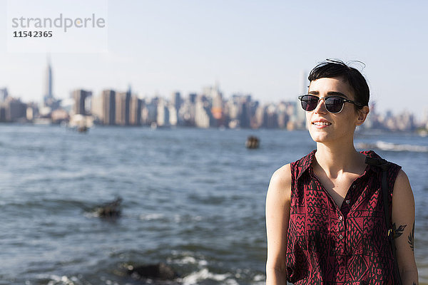 USA  New York City  Portrait einer lächelnden jungen Frau mit Sonnenbrille