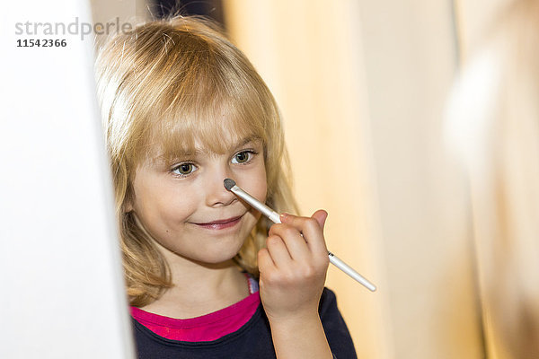 Spiegelbild des lächelnden kleinen Mädchens beim Schminken