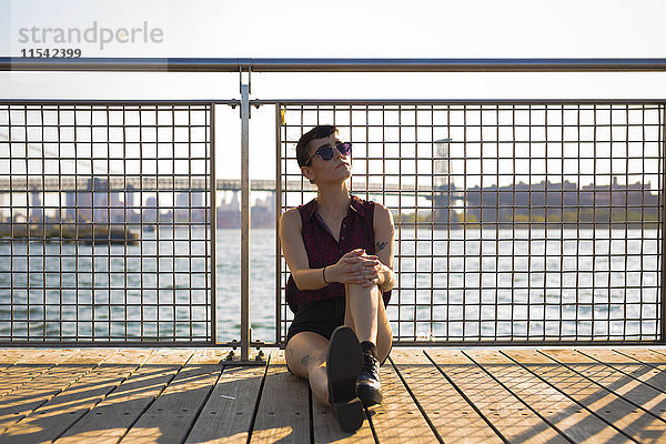USA  New York City  Williamsburg  Portrait einer tätowierten jungen Frau  die sich am Geländer lehnt