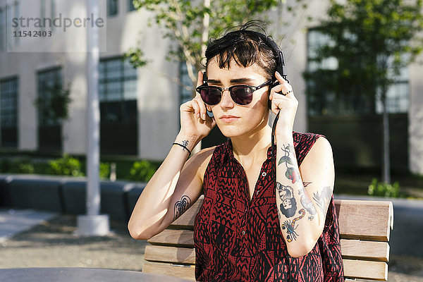 USA  New York City  Williamsburg  Portrait einer tätowierten jungen Frau mit Kopfhörer
