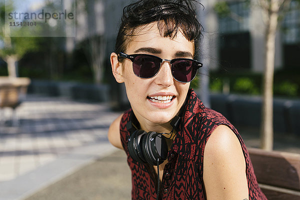 Porträt einer jungen Frau mit Kopfhörer und Sonnenbrille