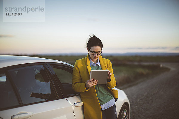 Frau mit digitalem Tablett im Auto
