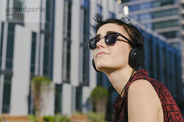 Portrait einer jungen Frau mit Kopfhörer und Sonnenbrille