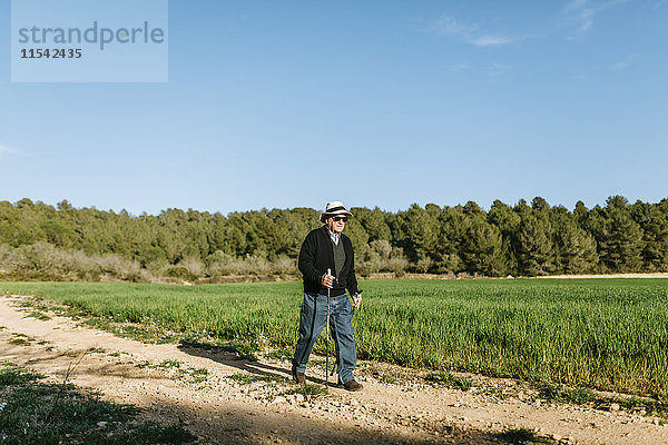 Spanien  Tarragona  Senior Mann  der mit Stöcken auf dem Feld geht