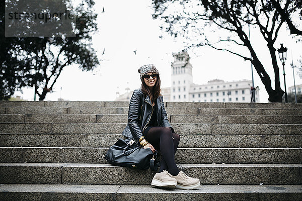 Spanien  Barcelona  lächelnde junge Frau auf der Treppe sitzend