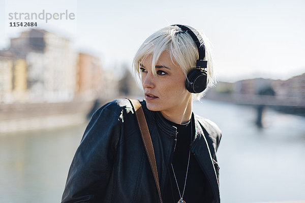 Italien  Verona  Portrait einer blonden Frau beim Musikhören mit Kopfhörern